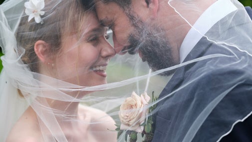 A bride and groom looking at each other under a veil